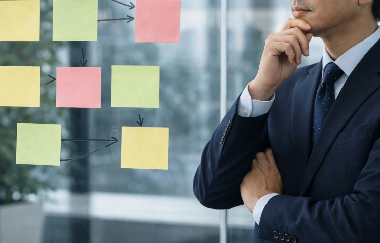 情報を整理したポストイットを見て事業承継の進め方を考えるコンサルタント