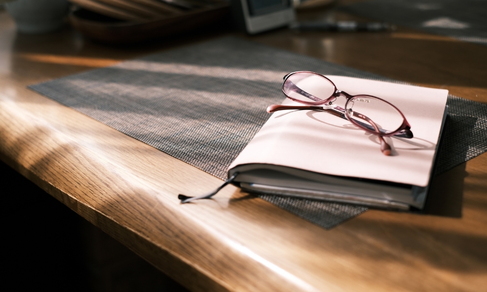 課題の認識をするため、机の上に置かれた眼鏡とノート
